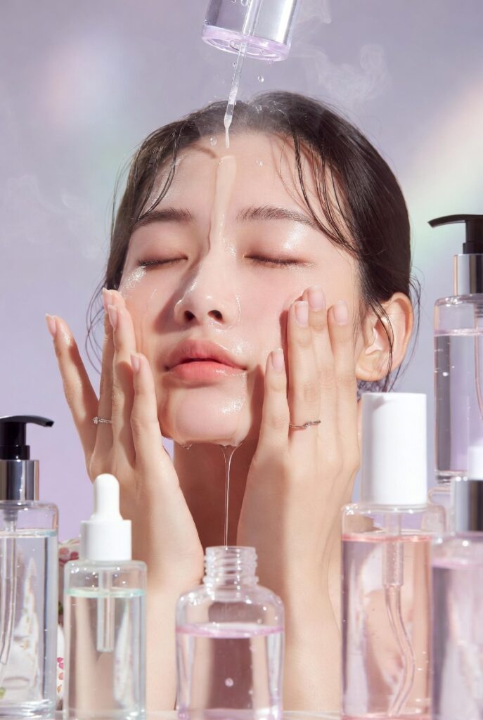 A glowing woman with dewy glass-like Korean skin surrounded by elegant skincare products including toners, serums, and botanicals, representing 20 Korean skin care ideas for a naturally radiant complexion.